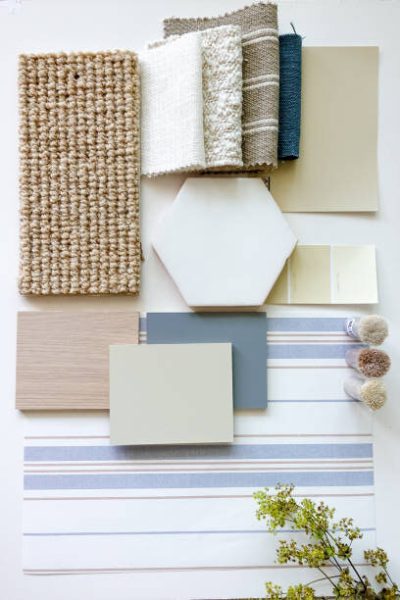 Texture and material samples for interior design projects, such as rugs, wallpaper, fabric and tiles, laid out to illustrate a modern soft blue beach house styling scheme